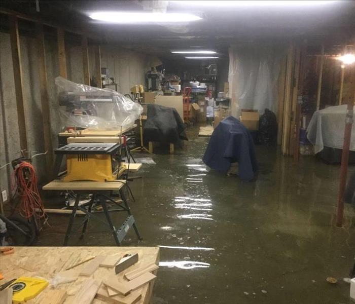 Home basement with personal belongings partially submerged in water.